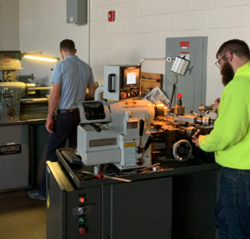 Team members using the lathe